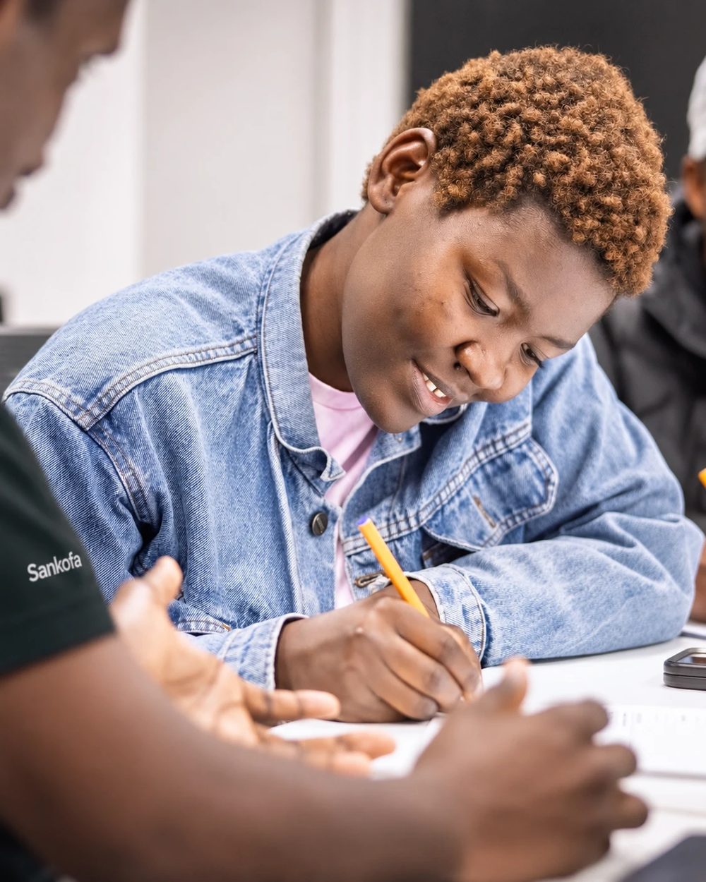 A participant writing notes while a Sankofa facilitator talks her through a resume