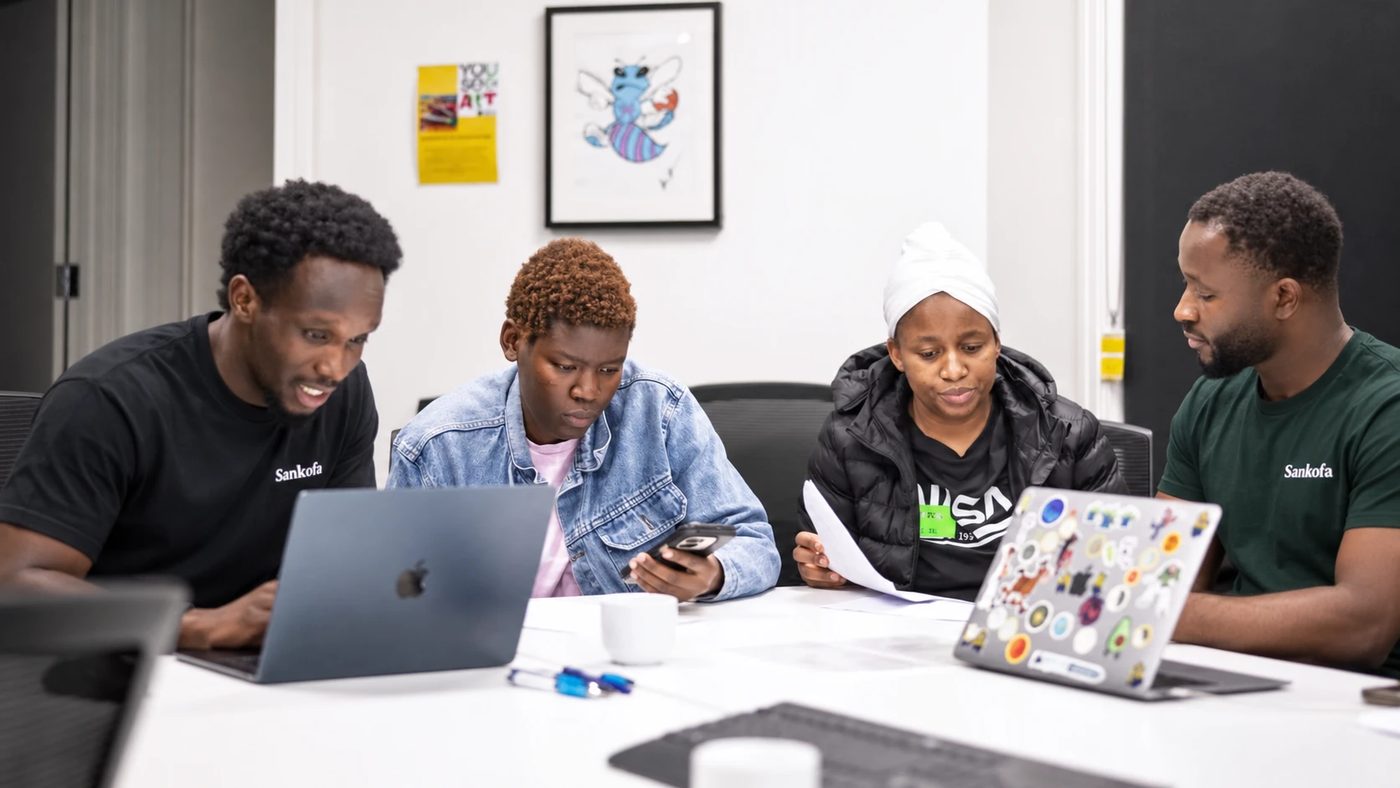 Two Sankofa facilitators and two participants working around a table with laptops